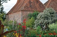 Kulisu zahradě vytvářejí budovy s výraznými bílými věžičkami na vrcholech střech. Jsou to staré sušárny chmelu, který se v této oblasti kdysi hojně pěstoval.